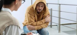 hooded man bent over with doctor