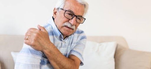 older man holding shoulder in pain