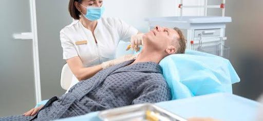 man laying in hospital bed getting injection in his neck