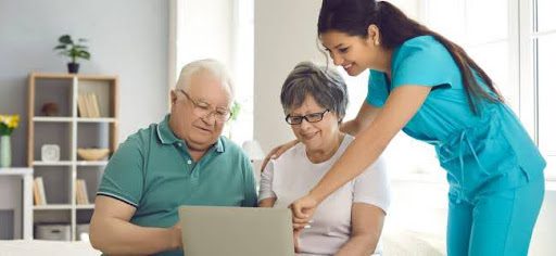 nurse helping older couple use computer