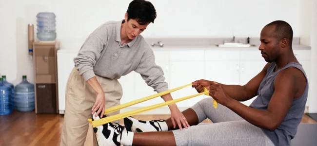 How Long Does an Epidural Steroid Injection Last? 3 Physical therapist guiding a patient through resistance band exercises to support long-term back pain relief after an epidural steroid injection
